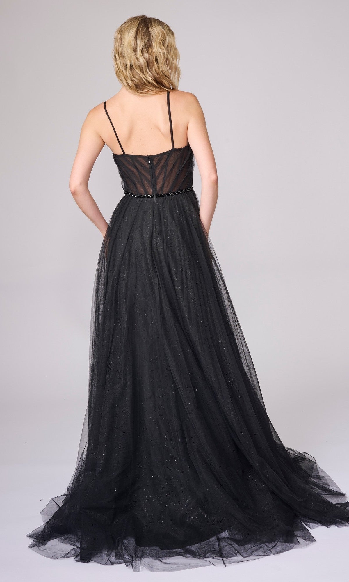 A woman with wavy blonde hair, seen from the back against a plain background, wears the Nina Canacci 5401: a sleeveless, ankle-length black A-line formal dress with thin straps.